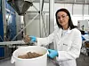 Empa-Forscherin Yuliia Dudnyk greift eine Handvoll flockige Lignocellulose aus einem Eimer
