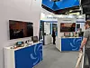 Messestand mit technischen Messgeräten, Monitoren und Besuchern in einer Messehalle