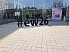 Große schwarze Hashtag-Skulptur #ew26 vor einem modernen Glasgebäude