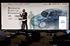 Redner spricht auf der Automotive Computing Conference 2026 vor Grafik eines Autos.