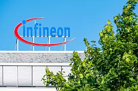 Infineon-Logo auf einem Gebäudedach in Frankfurt, teilweise von Bäumen verdeckt.