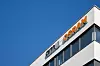 Eckansicht eines ams-Osram-Firmengebäudes mit Logo vor blauem Himmel.