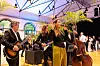 Liveband beim Abendprogramm der Internationalen Fachkonferenz „Bordnetze im Automobil“ 2026 in Ludwigsburg mit Sängerin am Mikrofon, Gitarristen, Kontrabass, Palmen-Dekoration, Lichtinstallation und Gästen im Hintergrund; stimmungsvolle Networking-Veranstaltung des Bordnetzkongresses für Automobilindustrie, Zulieferer, Bordnetz- und Leitungssatz-Experten