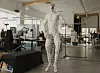 Humanoider weißer Roboter mit freiliegender Muskulatur in einer hellen Werkstatt.