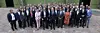 Gruppe von Geschäftsleuten posiert im Freien für ein offizielles Foto vor einem Gebäude.