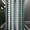 Nahaufnahme einer linearen Sprühanlage mit mehreren Düsen zur Reinigung dicht bestückter Elektronik.