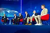 Podiumsdiskussion zum Thema Chiplets auf der Bühne des 30. AUTOMOBIL-ELEKTRONIK Kongresses 2026 in Ludwigsburg. Sechs Diskussionsteilnehmer sitzen auf roten Sesseln vor einem großen blauen Bühnenhintergrund mit stilisierter Fahrzeuggrafik, Netzwerklinien und Sponsorlogos. Links moderiert ein Teilnehmer die Runde, während die übrigen Panelisten aufmerksam zuhören oder in Richtung Moderator blicken. Die Szene zeigt eine fachliche Diskussion über Chiplets, Automotive Computing, Fahrzeugrechner, Halbleiterarchitekturen, Software-defined Vehicles, Skalierbarkeit, Standardisierung, Integration, Lieferketten und künftige E/E-Architekturen im Auto. Das Bild eignet sich für Beiträge über den 30. AUTOMOBIL-ELEKTRONIK Kongress, AEK 2026, Podiumsdiskussionen, Automotive-Halbleiter, Chiplet-Technologie, Fahrzeugplattformen, KI im Auto und den Branchenaustausch in Ludwigsburg.