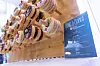 Donut-Wand im Cateringbereich des 30. AUTOMOBIL-ELEKTRONIK Kongresses 2026 in Ludwigsburg. Mehrere glasierte Donuts mit verschiedenen Toppings hängen an Holzstiften auf einer hellen Holzwand. Rechts daneben steht ein Schild mit der Aufschrift „Grab a Donut“ und dem Logo von Texas Instruments sowie verschiedenen Sorten wie Berry Bobby, Black Sensation, Cheesecake, Donutella und Pistachio. Die Aufnahme zeigt das Cateringangebot für die Teilnehmer des Kongresses und eignet sich als Schmuckbild für Berichte über den AEK, den AUTOMOBIL-ELEKTRONIK Kongress, Pausenverpflegung, Networking, Catering, Texas Instruments, Kongressatmosphäre, Teilnehmer, Fachveranstaltung, Automotive-Community und Branchentreff in Ludwigsburg.
