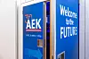 Zwei geöffnete Türen führen in den Konferenzsaal des 30. AUTOMOBIL-ELEKTRONIK Kongresses 2026 in Ludwigsburg. Auf der linken Tür ist das AEK-Logo mit dem Hinweis auf 30 Jahre AUTOMOBIL-ELEKTRONIK Kongress sowie das Datum 16. und 17. Juni 2026 zu sehen. Auf der rechten Tür steht in großen weißen Buchstaben „Welcome to the FUTURE“. Durch den schmalen Türspalt ist im Hintergrund blau-violettes Bühnenlicht aus dem Veranstaltungssaal zu erkennen. Das Bild eignet sich als atmosphärisches Schmuckbild für Beiträge über den Start in den Kongresstag, den Zugang zum Veranstaltungssaal, Zukunftsthemen der Automobilindustrie, Fahrzeugelektronik, Software-defined Vehicles, KI im Auto, E/E-Architekturen, Automotive Innovation, Kongressatmosphäre, 30 Jahre AEK, Ludwigsburg und den AUTOMOBIL-ELEKTRONIK Kongress 2026.