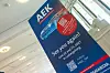 Ein großes blaues Werbeschild kündigt den nächsten AUTOMOBIL-ELEKTRONIK Kongress 2027 in Ludwigsburg an. Auf dem Plakat stehen das AEK-Logo, der Hinweis „See you again!“, das Datum 22. und 23. Juni 2027 in Ludwigsburg sowie ein QR-Code für die Anmeldung beziehungsweise weitere Informationen. In einem roten Kreis wird ein exklusiver Rebooker Discount beworben, gültig bis Juni 2027. Unten auf dem Schild sind der Hashtag #AEK_live, ein weiterer QR-Code und das Branding des Veranstalters beziehungsweise Medienpartners zu erkennen. Das Plakat steht in einem hellen Innenraum mit Treppe, Glasflächen und Tageslicht. Das Bild eignet sich für Beiträge über den Folgetermin des AUTOMOBIL-ELEKTRONIK Kongresses, AEK 2027, Ludwigsburg, Rebooking, Kongressankündigung, Automotive-Fachveranstaltung, Fahrzeugelektronik, Software-defined Vehicles, KI im Auto, Automotive Networking, Eventmarketing und die Fortsetzung des AEK nach dem Jubiläumsjahr 2026.