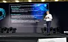 Jean-Marie Saint-Paul, Senior Vice President of EDA Global Sales bei Siemens EDA, spricht auf einer Bühne vor einer großen Präsentationsfolie mit Diagrammen und Text.