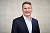 Florian Weig, SVP Purchasing and Supplier Network Digital bei BMW, ist auf einem professionellen Porträtfoto vor einem hellen, neutralen Hintergrund zu sehen. Er trägt einen dunkelblauen Anzug mit weißem Hemd, blickt freundlich in die Kamera und lächelt. Das Bild zeigt Florian Weig als BMW-Manager und Ansprechpartner für Purchasing, Supplier Network Digital, Elektronik-Beschaffung, Halbleiter, Software, KI, digitale Lieferketten und automobile Wertschöpfungsketten. Das Porträt eignet sich für ein Interview über BMW, die Neue Klasse, Automotive Electronics, Beschaffung automobiler Elektronik, Halbleiterstrategie, Elektronik-Lieferkette, geopolitische Spannungen, steigende Kosten, technologische Komplexität, globale Skalierung, regionale Anpassung, chinesische digitale Ökosysteme, Software-defined Vehicles, KI im Fahrzeug, Chiplets, CHASSIS-Initiative, Standards, Partnernetzwerke, Zuliefererbeziehungen, Supply Chain Resilience, Transparenz in der Wertschöpfungskette, Zusammenarbeit zwischen OEMs und Partnern sowie die Rolle von Florian Weig beim AUTOMOBIL-ELEKTRONIK Kongress.