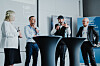 Vier Personen stehen an Stehtischen und diskutieren bei einem Live-Talk über ESG vor einer Präsentationswand.