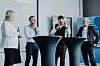 Vier Personen stehen an Stehtischen und diskutieren bei einem Live-Talk über ESG vor einer Präsentationswand.