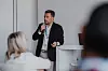 Mann spricht an einem Stehpult vor Publikum in einem Konferenzraum.