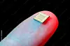Ein kleiner Mikrochip liegt auf einer fingerförmigen Oberfläche vor dunklem Hintergrund.