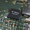 Nahaufnahme eines Infineon-CoolGaN-Chips auf einer grün bestückten Leiterplatte mit kleinen Bauteilen und Leiterbahnen.