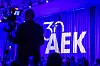 Bühne mit blau-violetter Beleuchtung, großem „30 JAHRE AEK“-Logo und einer Silhouette im Vordergrund.
