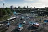 Mehrere Fahrzeuge fahren an einer großen Kreuzung, darüber sind blaue digitale Netzlinien eingeblendet.