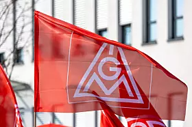 Rote IG Metall Fahne vor einem Industriegebäude als Symbolbild für die Tarifrunde 2026 in der Metall und Elektroindustrie, die Kündigung der Entgelttarifverträge durch die IG Metall, bevorstehende Tarifverhandlungen für rund 3,8 Millionen Beschäftigte, Forderungen nach höheren Entgelten, Kaufkraftsicherung und Beschäftigungssicherung sowie die angespannte wirtschaftliche Lage der M+E Industrie mit Rezession, schwacher Nachfrage, hohen Standortkosten und Strukturkrise in Deutschland.