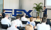 Redner vor Publikum in einem Konferenzraum neben großem FXE-Logo.