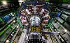 Blick auf den geöffneten CMS-Detektor am CERN in der Schweiz mit ringförmig angeordneten Detektormodulen, Kabelbündeln, Elektronikkomponenten, Wartungsplattformen und technischer Infrastruktur in einer großen unterirdischen Experimentierhalle. Der CMS-Detektor steht an einem Kollisionspunkt des Large Hadron Collider und misst die Teilchen, die bei Proton-Proton- und Schwerionenkollisionen entstehen. Zu sehen sind die komplexe mechanische Struktur, zahlreiche Leitungen, Versorgungs- und Auslesesysteme sowie Arbeitsbereiche für Technikerinnen und Techniker. Das Bild veranschaulicht, warum der Umbau zum High-Luminosity LHC nicht nur den Beschleunigerring betrifft, sondern auch die Detektoren selbst: Sensoren, Front-End-Elektronik, Readout-Chips, Trigger-Systeme, Datenübertragung, Stromversorgung und Kühlung müssen künftig deutlich höhere Kollisionsraten und größere Datenmengen bewältigen. Der CMS-Detektor wird dafür modernisiert, damit er ab 2030 Ereignisse mit höherer Granularität, präziserem Timing und leistungsfähigeren Auslesesystemen erfassen kann.