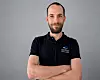 Jan Claes, Director Testing & Certification bei BitifEye Digital Test Solutions, steht mit verschränkten Armen vor neutralem grauem Hintergrund und trägt ein dunkelblaues Polo-Shirt mit BitifEye-Logo. Das Porträt zeigt den Experten für Physical-Layer-Testing und Compliance-Prüfungen digitaler Hochgeschwindigkeitsschnittstellen im Kontext von MIPI A-PHY, PCIe und Automotive-SerDes-Testverfahren.