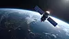 Ki-generierte symbolische Darstellung eines Satelliten im niedrigen Erdorbit mit zwei großen, blau schimmernden Solarmodulen vor der gekrümmten Erde. Unter dem Raumfahrzeug sind Wolken, Ozeane, Küstenlinien und beleuchtete Städte auf der Nachtseite des Planeten zu erkennen, während Sonnenlicht den Horizont und Teile des Satelliten erhellt. Das Bild steht für die BOHR-Mission von City Labs, bei der ein Kleinsatellit eine betavoltaische Nuklearbatterie auf Basis des radioaktiven Wasserstoffisotops Tritium im All testet. Die Solarzellen versorgen weiterhin den Satellitenbus und damit die grundlegenden Systeme des CubeSats, während die Tritium-Batterie ausschließlich eine separate experimentelle Nutzlast mit sehr geringer, über viele Jahre verfügbarer elektrischer Leistung speist. Bei der NanoTritium-Technologie werden die beim radioaktiven Zerfall des Tritiums freigesetzten Beta-Teilchen von einer Halbleiterstruktur direkt in elektrischen Strom umgewandelt. Die Mission soll zeigen, wie zuverlässig eine solche langlebige Mikrostromquelle unter den Strahlungs-, Temperatur- und Vakuumbedingungen des Weltraums arbeitet. Das abgebildete Raumfahrzeug ist eine illustrative Darstellung und zeigt nicht den tatsächlichen BOHR-CubeSat.