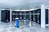 Ein Blick ins Rechenzentrum der TU Dresden: Halbkreisförmig angeordnete Serverschränke des Hochleistungsrechners blinken im Takt ihrer Berechnungen, während das Touch Panel im Vordergrund die Systemdaten visualisiert.