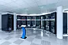 Ein Blick ins Rechenzentrum der TU Dresden: Halbkreisförmig angeordnete Serverschränke des Hochleistungsrechners blinken im Takt ihrer Berechnungen, während das Touch Panel im Vordergrund die Systemdaten visualisiert.