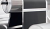 Nahaufnahme einer industriellen Maschine mit Metallrollen und dunklen Paneelen in einer Produktionsumgebung.