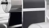 Nahaufnahme einer industriellen Maschine mit Metallrollen und dunklen Paneelen in einer Produktionsumgebung.