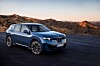 Blauer BMW-SUV auf einer Straße in einer trockenen Berglandschaft bei Abendlicht.