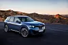 Blauer BMW-SUV auf einer Straße in einer trockenen Berglandschaft bei Abendlicht.