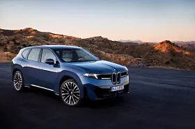 Blauer BMW-SUV auf einer Straße in einer trockenen Berglandschaft bei Abendlicht.
