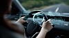 Person steuert in einem modernen Auto ein holografisches Dashboard mit digitalen Anzeigen.