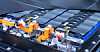 Nahaufnahme eines Batteriemoduls mit Kabeln und orangefarbenen Befestigungen auf einer Metallplatte.