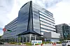 Modernes Bürogebäude mit Glasfront an einer Straße, davor ein Wistron-Schild und einige Fahrzeuge.