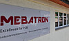 Schild mit MEBATRON-Logo an einer hellen Gebäudeaußenwand neben Fenstern.