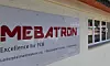 Schild mit MEBATRON-Logo an einer hellen Gebäudeaußenwand neben Fenstern.