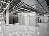 Serverraum mit Metallgitterwänden, Kabeltrassen an der Decke und glänzendem Boden.