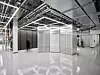 Serverraum mit Metallgitterwänden, Kabeltrassen an der Decke und glänzendem Boden.