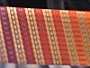 Nahaufnahme eines orange-roten Textilmusters mit geometrischen Streifen und wiederholten Formen.