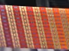 Nahaufnahme eines orange-roten Textilmusters mit geometrischen Streifen und wiederholten Formen.