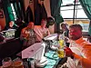 Gruppe von Gästen in einer Bar hebt Gläser an einem gedeckten Tisch mit Fenstern im Hintergrund.