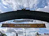 Grüner Eingangsbogen mit dem Schriftzug „Willkommen zum Oktoberfest“ vor blauem Himmel.