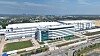 Luftbild eines großen Industrieareals mit modernen Hallen, Bürogebäude und Verkehrsflächen.