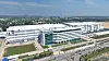 Luftbild eines großen Industrieareals mit modernen Hallen, Bürogebäude und Verkehrsflächen.