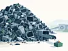 Großer Stapel aus alten Computern und Elektronikschrott neben einem Recyclingcontainer.