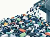 Haufen aus Elektroschrott mit Geräten, Kabeln und Batterien in einer Recyclinganlage.